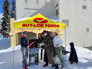 Parent volunteers barbequing under a Buy Low Foods tent